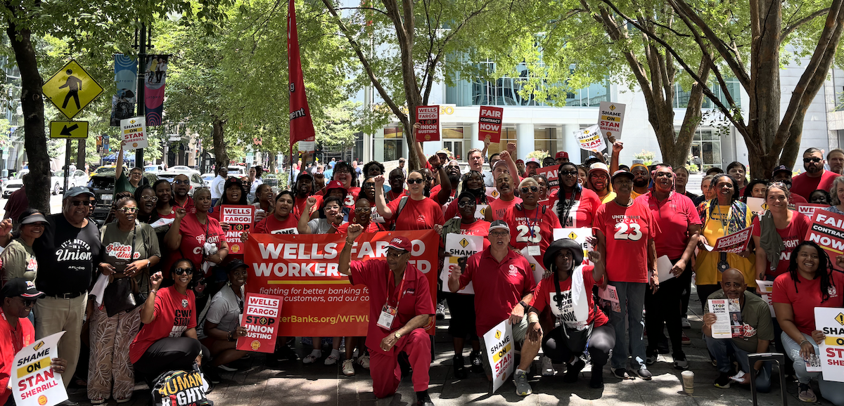A large group wearing red with banners and signs and flags pose for the camera