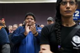 two people are stonefaced while another claps and smiles.