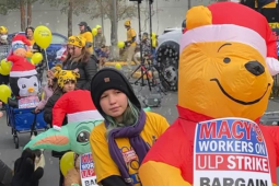 A line of children and adults push baby carriages with inflatable animals wearing signs saying ‘Macy’s Workers on ULP Strike’