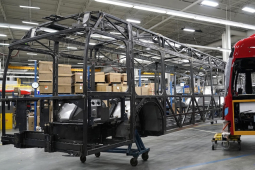The skeleton of an unfinished bus, and the outer shell of another are shown in a factory