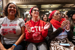 Five women sit applauding, one is wearing a CTU T-shirt, another says “we care” with a drawing of a chalkboard
