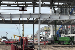 The skeleton of a giant building with a worker in a manlift is shown.