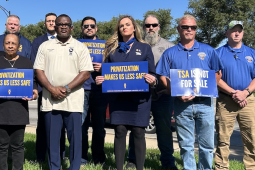 A group stands with signs against privatization of airport security