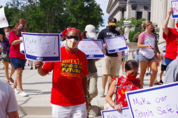 Teachers wearing masks hold signs that say Make Our Schools Safe and Not Until It's Safe.