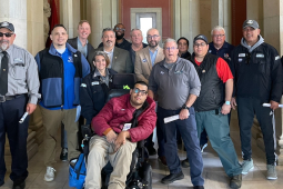 A group of 10 people poses for the camera.  One is in a wheelchair.