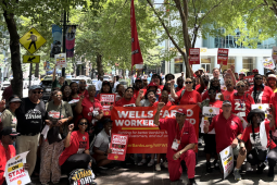 A large group wearing red with banners and signs and flags pose for the camera