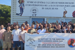 A group of workers hold a banner in front of a French banner. 