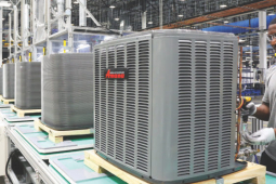A worker at an Asana heat pump assembly factory stands with a drill working on a heat pump