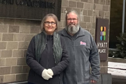 A couple stand by a wall with a Hyatt sign