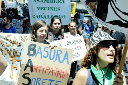 Several people with banners in Spanish march towards the camera’s right