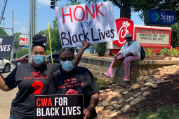 Two CWA members with signs for Black lives on the pavement