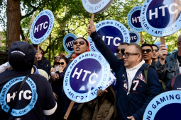 Several people chant with round Hotel Trades Council signs.