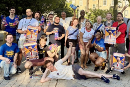 A group of around 30 canvassers pose with signs and fliers.