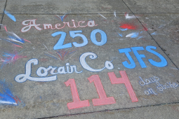 Chalk graffiti on sidewalk says “America 250, Lorain Co. JFS 114 days on strike”