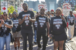 A group of autoworkers with black “Protect Our Freedom to Vote” shirts march