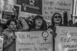 Workers hold signs in Spanish saying ‘we are workers not beggars’.