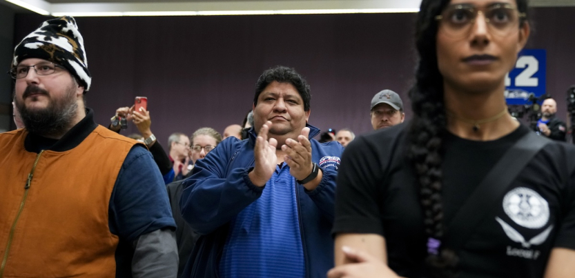 two people are stonefaced while another claps and smiles.