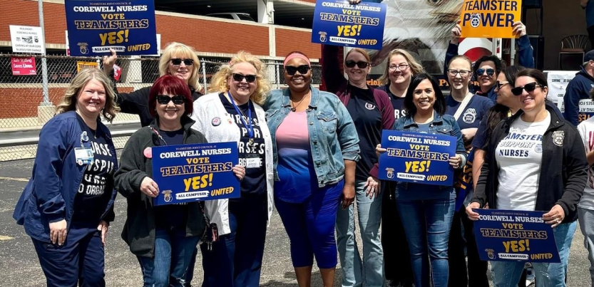 A dozen nurses with Teamsters signs face the camera, looking excited.