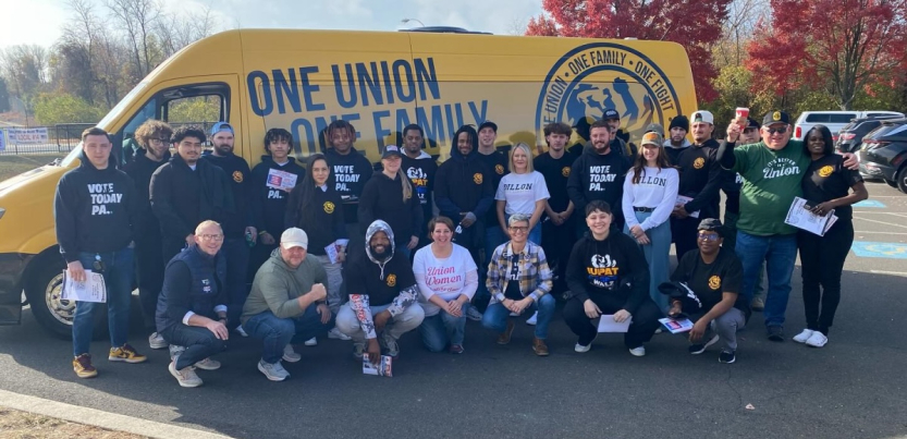 Thirty people pose with a yellow van behind them that says One Union, One Family