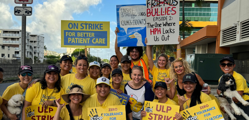 Nurses in yellow shirts pose smiling. Most are women; most appear Native Hawaiian or Asian. Many wear ballcaps. Some carry printed signs saying "ULP strike," "Zero tolerance for retaliation," or "on strike for better patient care." Two carry handmade signs--one with an image of a duck and the words "Unsafe staffing leads to quack-cidents," and the other with the logo of the show "Friends" crossed out, the word "Bullies" written in the same style, followed by "Episode 2: The One Where HPH Locks Us Out."