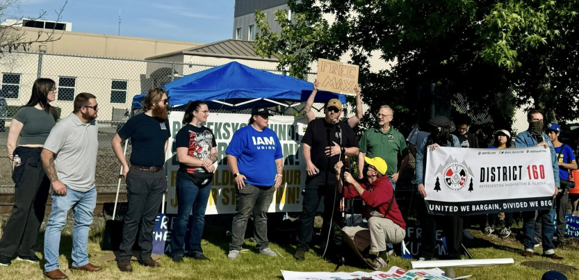 Ten people, some with Machinists Union shirts, stand with a Machinists Local 160 banner