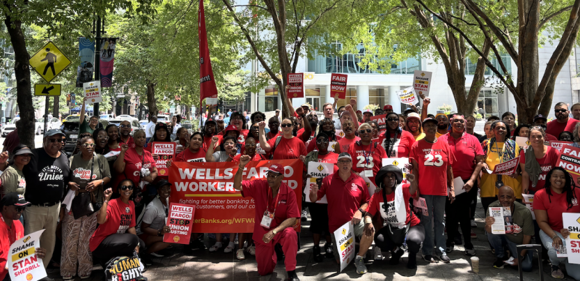 A large group wearing red with banners and signs and flags pose for the camera