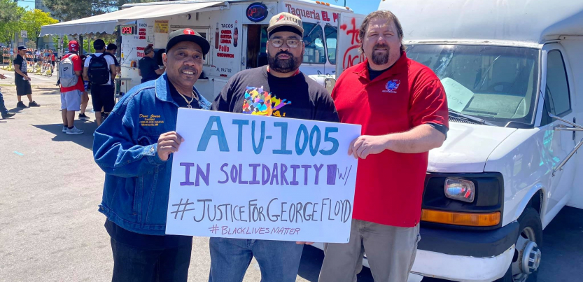 Three men (two Black, one white) hold a sign: "ATU-1005 in solidarity w/ #JusticeForGeorgeFloyd #BlackLivesMatter." Taco truck in background.