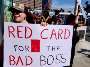 A worker holding a sign that says: Red card for the bad boss
