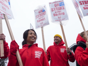 Five women and men in red hoodies that say “strike strike strike” hold picket signs