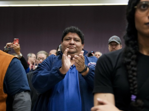 two people are stonefaced while another claps and smiles.