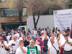 Workers gather with fists in the air and the union's flag flying behind them. 