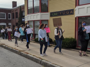 A group of teachers marches on the sidewalk in downtown Andover, Massachusetts.