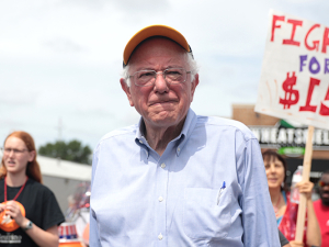 Photo of Bernie Sanders in front of Fight for $15 sign.