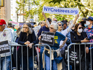a line of retirees protest behind a metal barrier