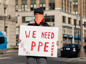 CWA protester holding a sign that says "We Need PPE"