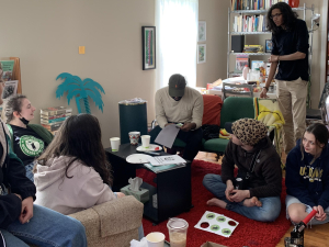 A group of Chipotle workers and supporters gather around a coffee table at a house to discuss their campaign.