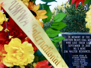 A wreath of flowers with a UMWA International sash around it sits in front of a monument to remember the 13 miners who lost their lives at the Jim Walter Resources No. 5 Mine in September 2001.