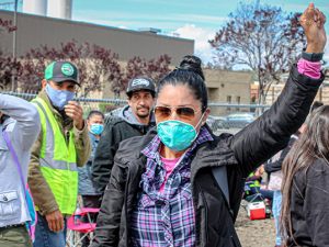 Woman with fist up amidst farmworkers on strike