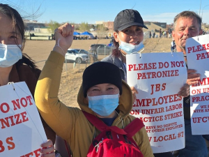 Four strikers holding signs, one with a fist in the air, face the camera.