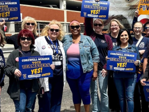 A dozen nurses with Teamsters signs face the camera, looking excited.