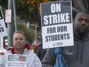 A white man and a Black man hold signs: "On Strike for Our Students; UTLA"