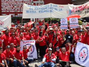A large crowd of SINTTIA members in red shirts hold banners celebrating May Day