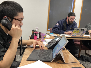 Three union activists sit around a table on their phones, making calls to drum up support for Initiative 1.