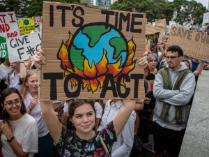 New Zealand students hold signs with slogans like "It's Time to Act," with a drawing of the earth being consumed by flames, during a school strike in March 2019.