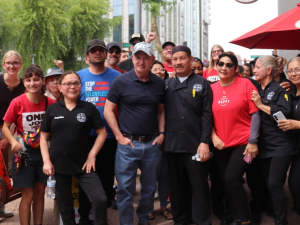 A group 25 of workers in red shirts gather near an umbrella saying Panda Express