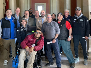 A group of 10 people poses for the camera.  One is in a wheelchair.