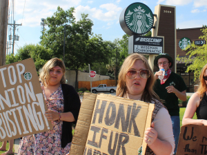 Striking Starbucks workers and supporters hold signs reading Stop Union Busting outside a store.