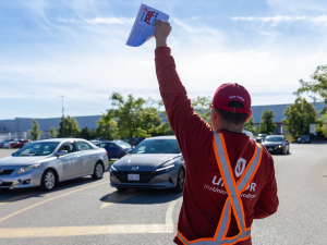 A worker holds a flyer in the air. His hat reads: "Vote Unifor"