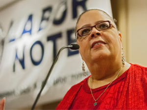 Karen Lewis at the podium in front of Labor Notes banner