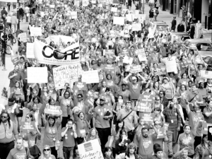 Black-and-white photo of huge crowd of Chicago teachers marching through a downtown street. Many carry signs. One large banner says "CORE," which stands for the Caucus of Rank-and-File Educators.